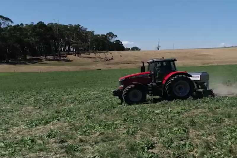 A tractor plowing a field, creating furrows in the soil.