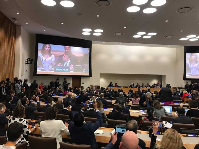 Many individuals gathered in a room with large screens.