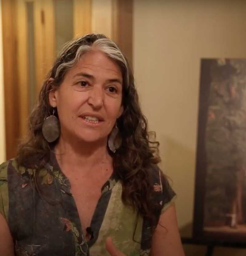 A woman with long hair, dressed in a green shirt, speaks about her commitment to advocating for nature.