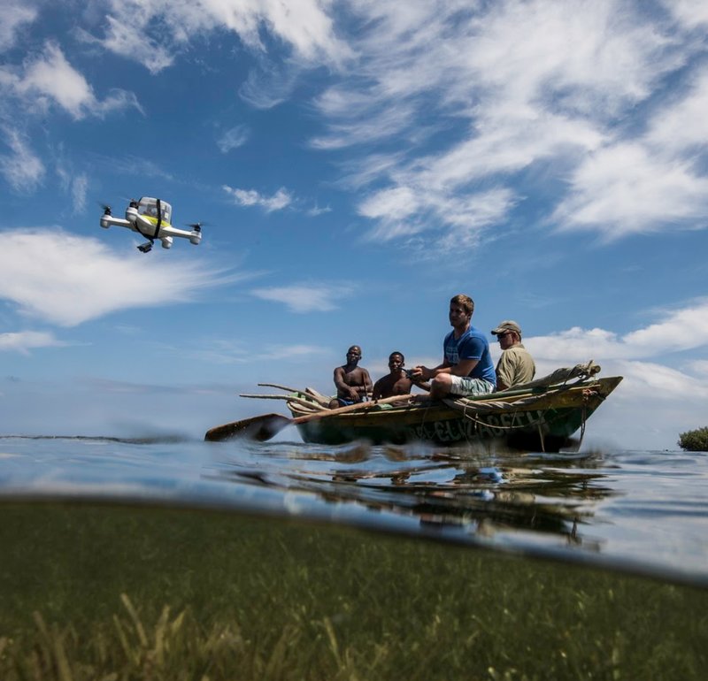A group of individuals in a boat enjoying the day while a drone hovers above them, capturing the moment from above.